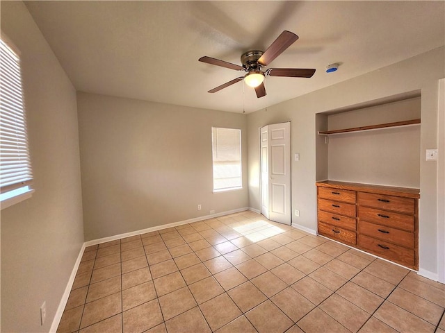 unfurnished bedroom with multiple windows, light tile patterned flooring, ceiling fan, and a closet