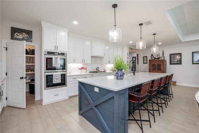 4101 Karo Dr, Corpus Christi, TX 78414 - kitchen featuring stainless steel appliances, recessed lighting, white cabinets, light wood finished floors, and a kitchen breakfast bar