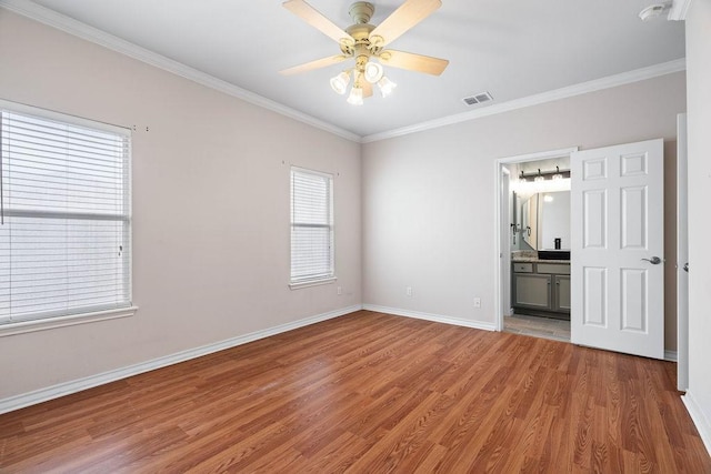 unfurnished bedroom with visible vents, ornamental molding, ensuite bathroom, light wood finished floors, and baseboards