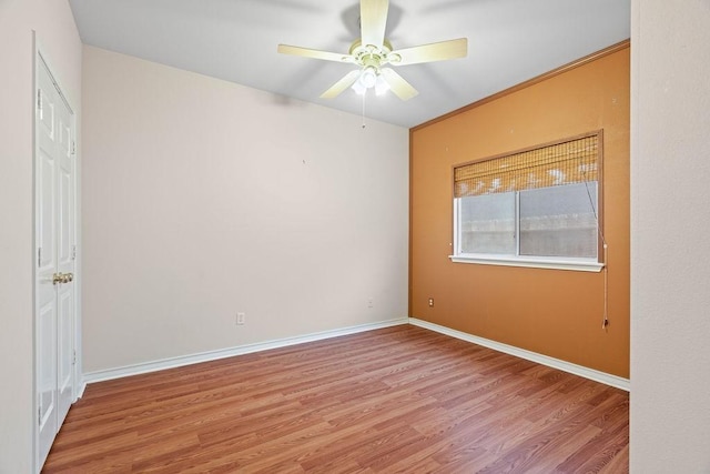 empty room featuring a ceiling fan, wood finished floors, baseboards, and ornamental molding