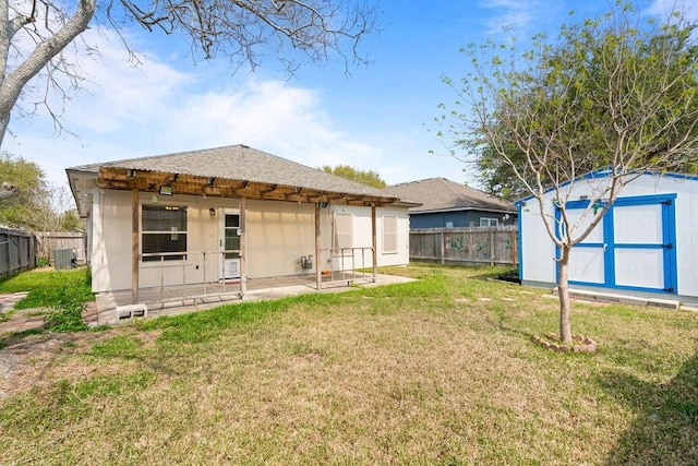 rear view of house with a storage unit, central air condition unit, a fenced backyard, a yard, and an outdoor structure