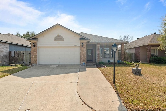 ranch-style house featuring brick siding, fence, concrete driveway, a front yard, and a garage