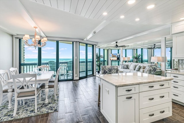 kitchen featuring dark wood-style flooring, ceiling fan with notable chandelier, white cabinetry, open floor plan, and expansive windows