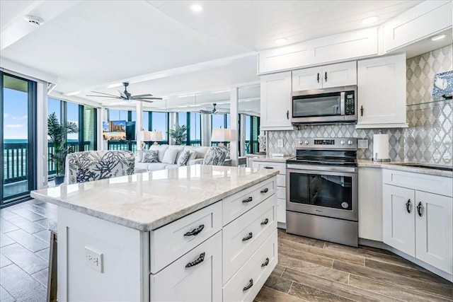 kitchen with ceiling fan, backsplash, stainless steel appliances, and white cabinetry