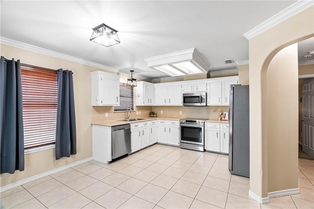 3837 Brockhampton Ct, Corpus Christi, TX 78414 - kitchen featuring stainless steel appliances, light countertops, light tile patterned floors, crown molding, and arched walkways
