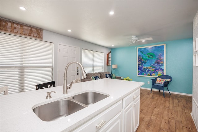 kitchen with white cabinetry, sink, ceiling fan, and light hardwood / wood-style flooring