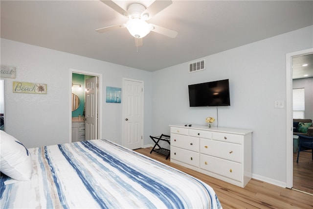 bedroom featuring light wood-type flooring, ensuite bath, and ceiling fan