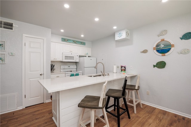 kitchen with white cabinets, kitchen peninsula, sink, a breakfast bar, and white appliances