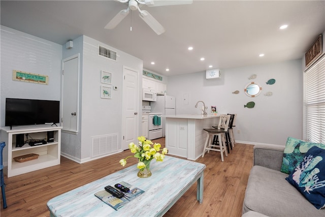 living room with light wood-type flooring, sink, and ceiling fan