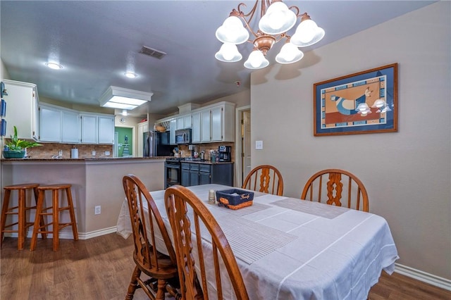 dining area with an inviting chandelier and dark hardwood / wood-style flooring