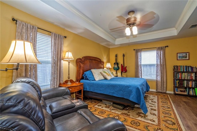 bedroom featuring ceiling fan, ornamental molding, a tray ceiling, and dark hardwood / wood-style flooring