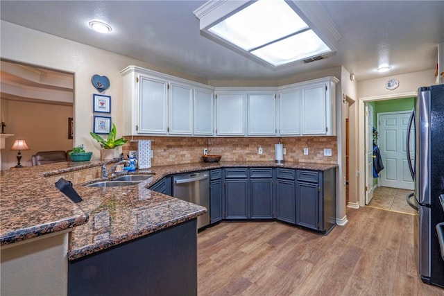 kitchen with blue cabinets, sink, white cabinets, kitchen peninsula, and stainless steel appliances