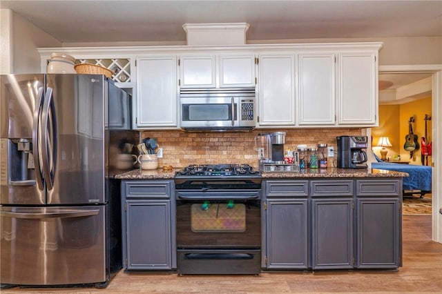 kitchen featuring appliances with stainless steel finishes, white cabinets, light hardwood / wood-style floors, and decorative backsplash