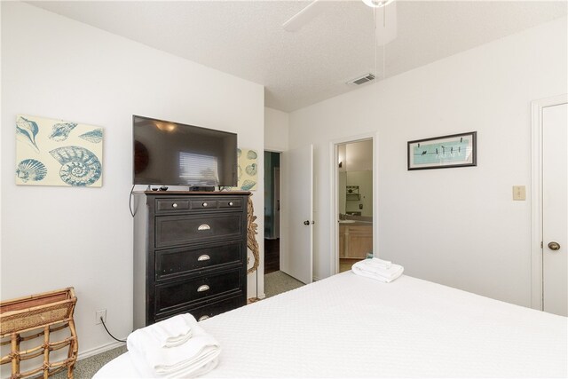 bedroom with carpet flooring, ensuite bath, a textured ceiling, and ceiling fan