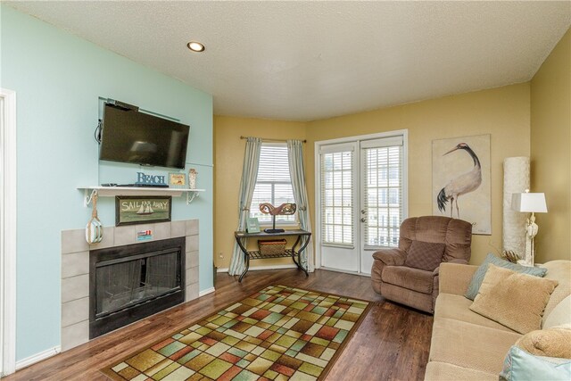 living room with dark hardwood / wood-style floors, a textured ceiling, and a tiled fireplace