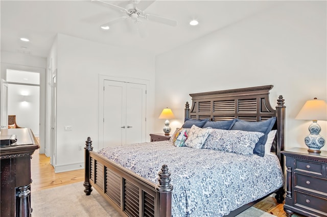 bedroom with a closet, light hardwood / wood-style floors, and ceiling fan