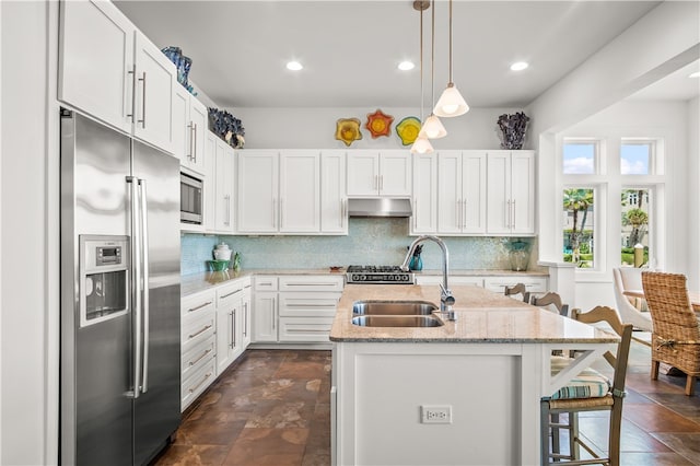 kitchen with stainless steel appliances, white cabinets, an island with sink, and sink