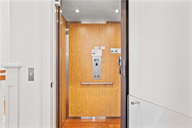 room details featuring wood walls, elevator, and hardwood / wood-style floors