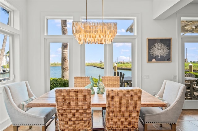 tiled dining space with a water view and an inviting chandelier