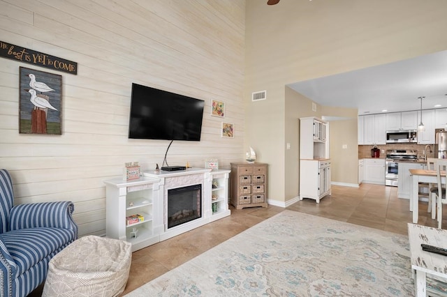 tiled living room featuring a towering ceiling and sink