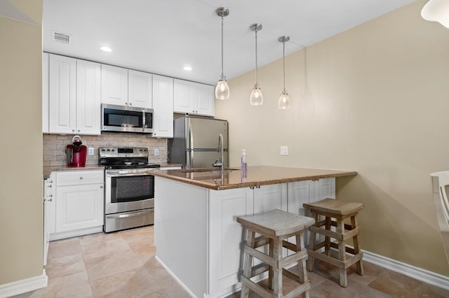 kitchen featuring white cabinets, a breakfast bar area, decorative backsplash, and appliances with stainless steel finishes