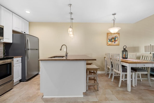 kitchen with pendant lighting, appliances with stainless steel finishes, sink, and white cabinets