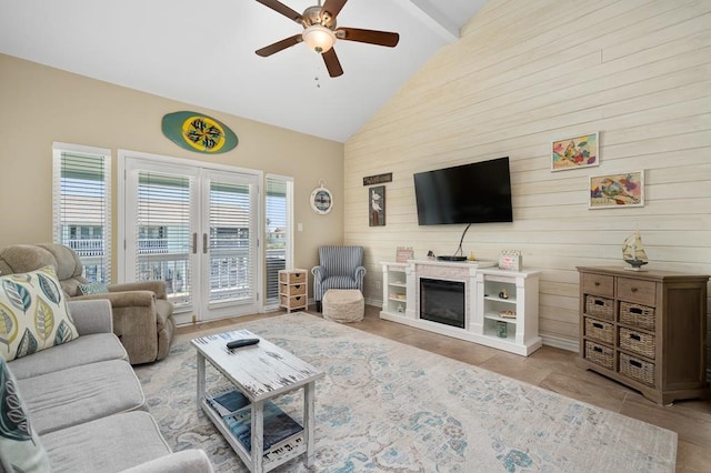 living room featuring wood walls, ceiling fan, beamed ceiling, and high vaulted ceiling