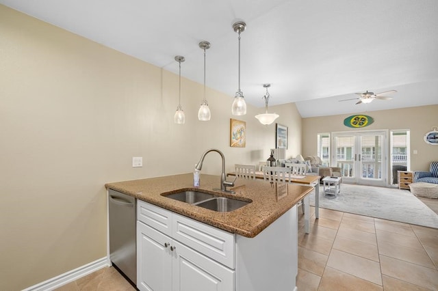 kitchen with dark stone counters, sink, stainless steel dishwasher, white cabinetry, and decorative light fixtures