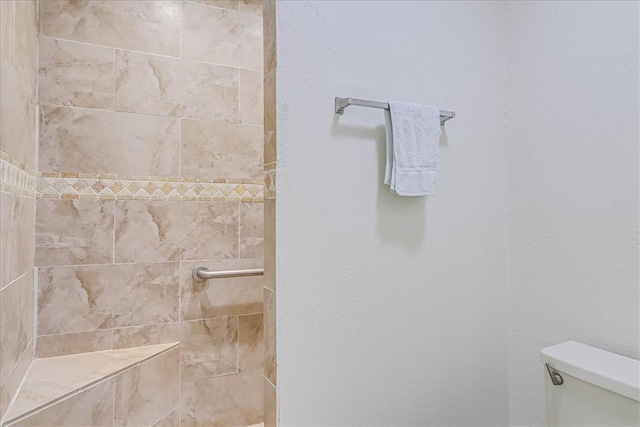 bathroom with toilet and tiled shower