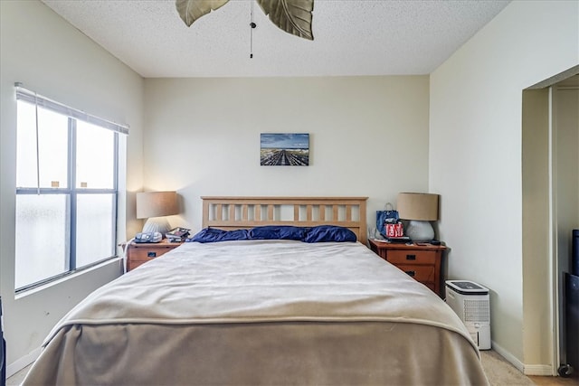 bedroom with ceiling fan, a textured ceiling, and light carpet