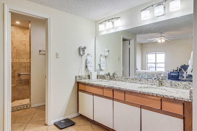 bathroom featuring ceiling fan, a textured ceiling, a tile shower, vanity, and tile patterned floors