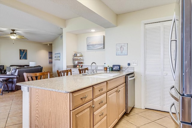 kitchen with light tile patterned flooring, appliances with stainless steel finishes, light brown cabinetry, sink, and kitchen peninsula