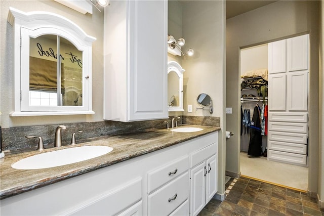 101 Bay Hills Dr, Rockport, TX 78382 - bathroom featuring double vanity, stone finish floors, and a walk in closet