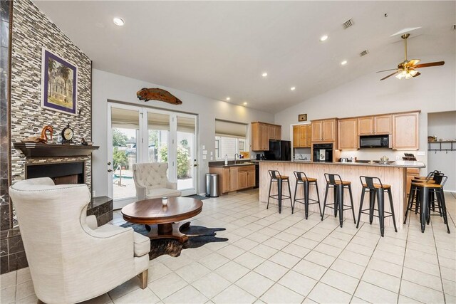 101 Bay Hills Dr, Rockport, TX 78382 - kitchen with black appliances, a breakfast bar, ceiling fan, light tile patterned floors, and light brown cabinetry
