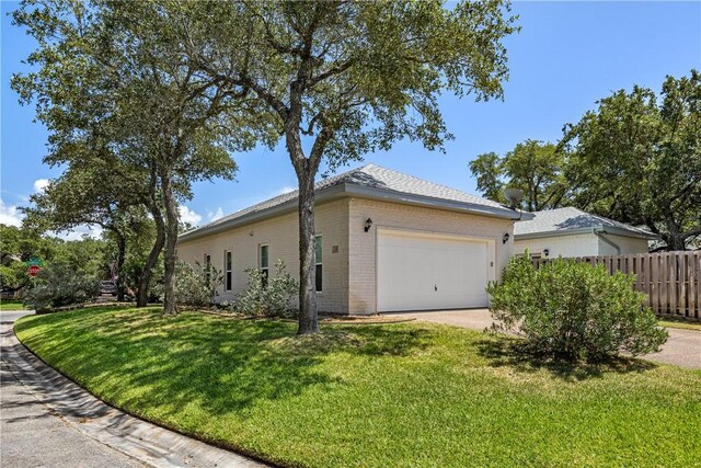 101 Bay Hills Dr, Rockport, TX 78382 - view of side of home featuring an attached garage, brick siding, and concrete driveway
