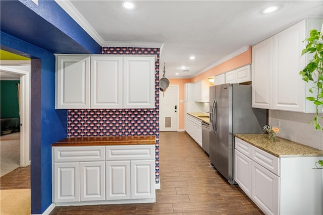 101 Llano Dr, Portland, TX 78374 - kitchen featuring stainless steel appliances, ornamental molding, tasteful backsplash, dark wood-style flooring, and white cabinets