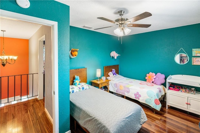 101 Llano Dr, Portland, TX 78374 - bedroom with a chandelier, wood finished floors, a textured wall, and a ceiling fan