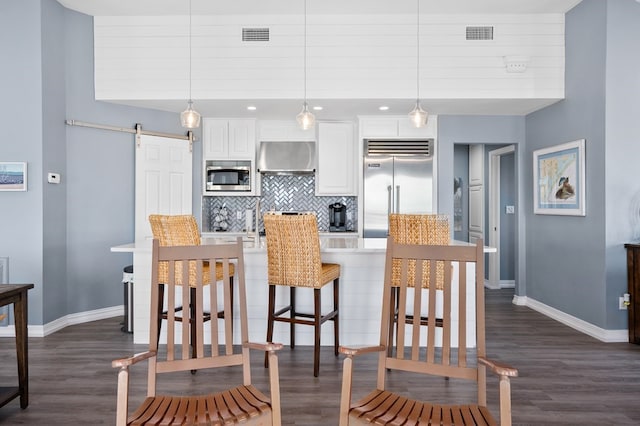 1819 Bay Shore Dr, Rockport, TX 78382 - kitchen featuring built in appliances, a barn door, baseboards, decorative backsplash, and dark wood finished floors