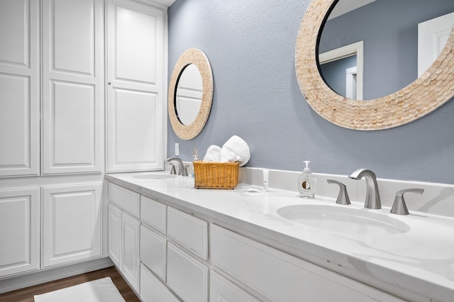 1819 Bay Shore Dr, Rockport, TX 78382 - full bath featuring double vanity, a textured wall, and wood finished floors