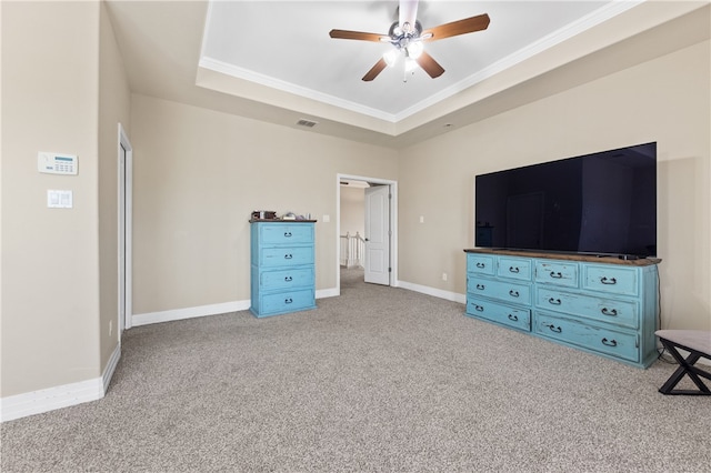 unfurnished bedroom featuring ceiling fan, light carpet, a raised ceiling, and ornamental molding