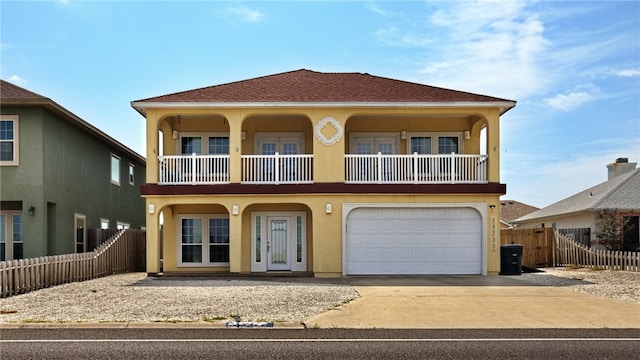 view of front facade with a balcony, french doors, and a garage