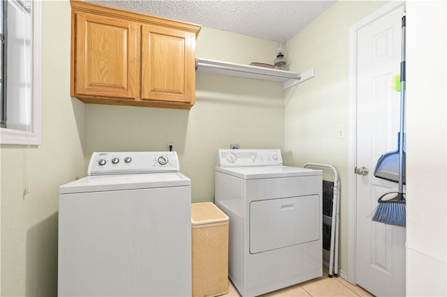 laundry area featuring cabinet space, a textured ceiling, light tile patterned flooring, and washer and clothes dryer