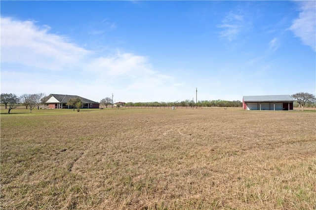 view of yard featuring a garage, an outbuilding, and a rural view