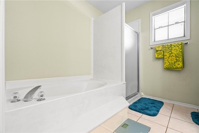 full bath with a shower stall, baseboards, a bath, tile patterned floors, and a textured ceiling