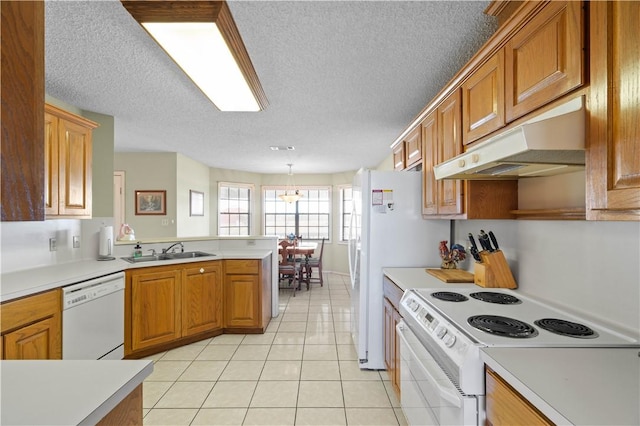 kitchen featuring under cabinet range hood, white appliances, a peninsula, and light countertops