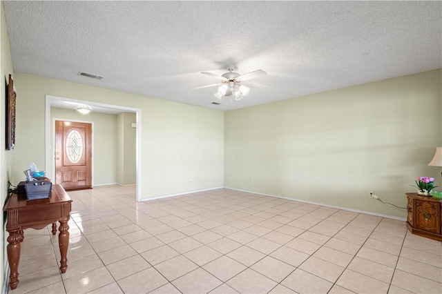 spare room with light tile patterned floors, baseboards, visible vents, ceiling fan, and a textured ceiling