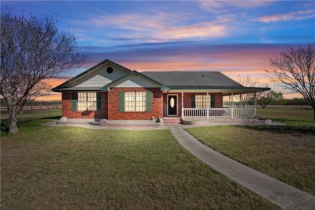 view of front of property with a yard, brick siding, and covered porch