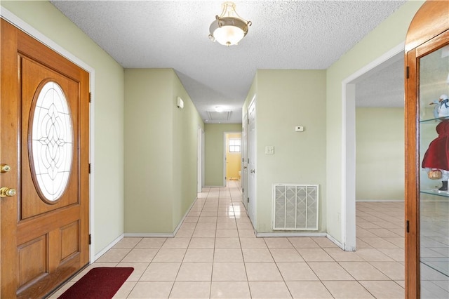 foyer featuring light tile patterned flooring, visible vents, a textured ceiling, and baseboards