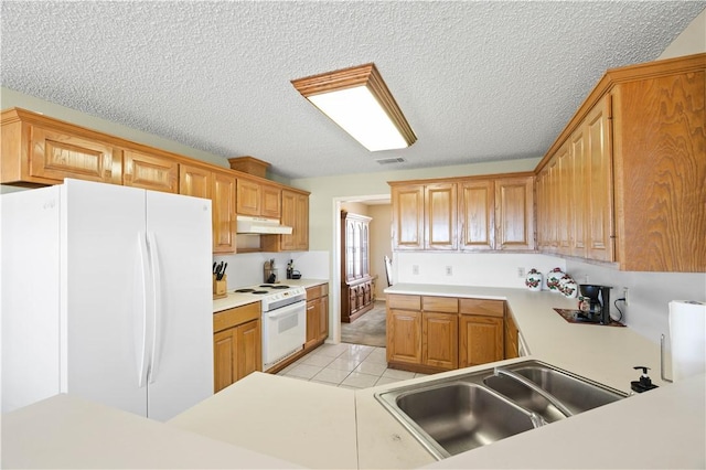 kitchen with under cabinet range hood, light tile patterned floors, white appliances, a textured ceiling, and a sink