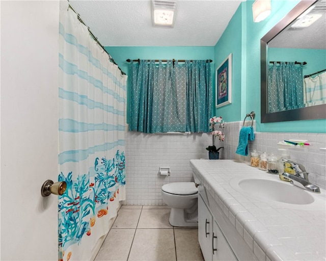 full bathroom featuring tile walls, vanity, a textured ceiling, tile patterned flooring, and shower / tub combo with curtain